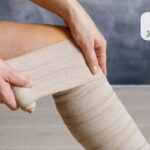 Person applying a beige elastic compression bandage around their calf/leg**