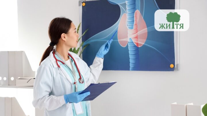 Female doctor in a white coat with blue gloves points at a lung anatomy diagram on a board, clipboard in hand